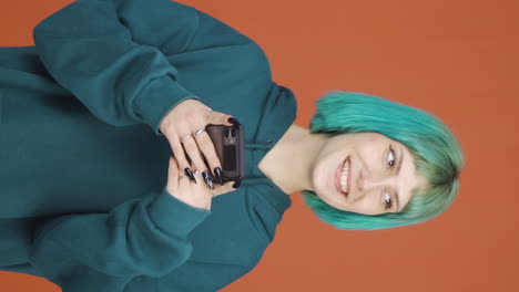 Vertical-video-of-Happy-young-woman-texting-on-the-phone.-Smiling.